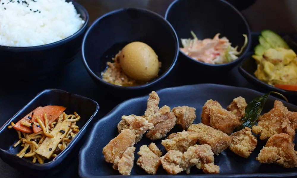 Crispy fried pork cutlet meal set with rice, soy egg, pickled veggies and assorted side dishes in black tableware at Princess Dumpling, a Asian Restaurant in Rowland Heights