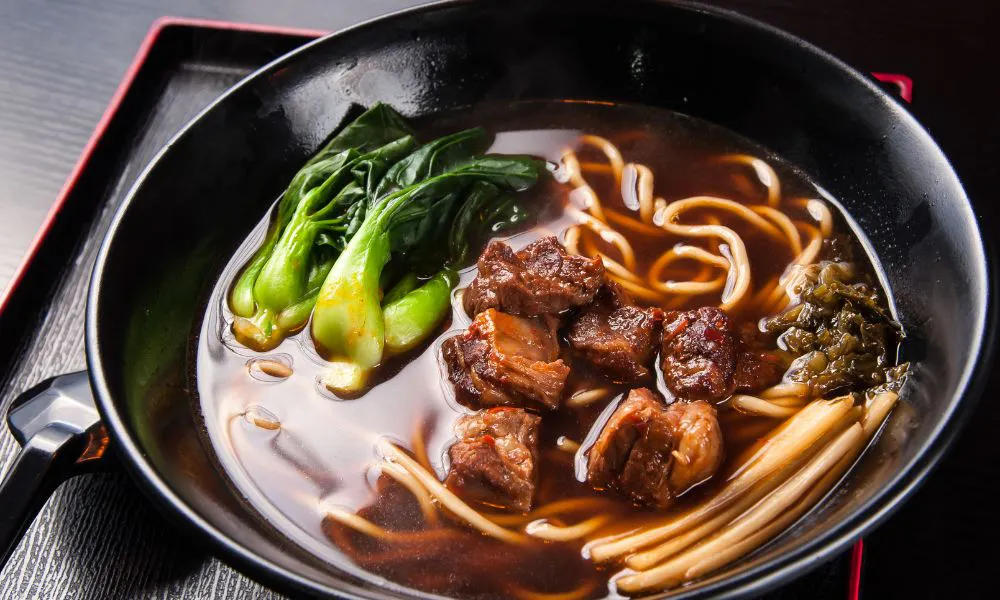 Black pot beef noodle soup with thick noodles, braised beef chunks, bok choy and preserved mustard greens at Princess Dumpling, a Asian Restaurant in Rowland Heights